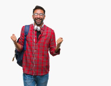 Üzerinde kulaklık ve sırt çantası giyiyor yetişkin İspanyol öğrenci adam şaşırmış ve başarı için hayran kaldırdı kollarını açarak kutlama arka plan izole ve gözleri açık. Kazanan kavramı.