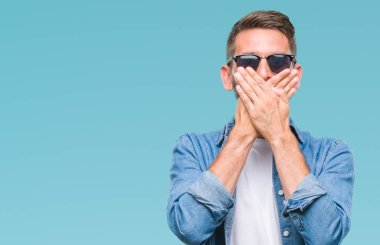 Yakışıklı delikanlı üzerinde güneş gözlüğü takıyor arka plan ağız hata için elleriyle kapsayan şok izole. Gizli kavramı.