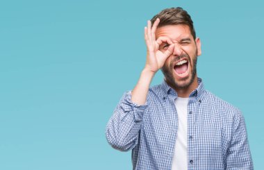 Sürpriz yüz, göz parmaklarının arasından seyir ile ok jest yapıyor izole arka plan üzerinde beyaz t-shirt giyen genç yakışıklı adam şok. İmansız ifade.