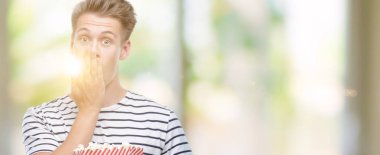 Genç yakışıklı sarışın adam yeme patlamış mısır kapak ağız el için hata, ifade korku, utanç ile şok ile sessizlik içinde gizli kavramı korkuttu