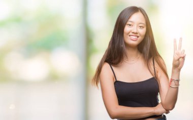 Genç Asyalı kadın mutlu yüz zafer işareti yaparken kameraya göz kırpıyor ile gülümseyen izole arka plan üzerinde. İki numaralı.