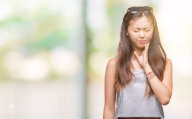 Genç Asyalı kadın diş ağrısı veya dişlerde dişlerle ilgili hastalık nedeniyle ağız acı ifadesi ile el ile dokunmak izole arka plan üzerinde güneş gözlüğü takıyor. Diş hekimi kavramı.
