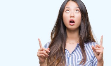 Genç Asyalı kadın izole arka plan üzerinden hayran ve yukarıya bakıp parmakları ile işaret şaşırttı ve silah kaldırdı.