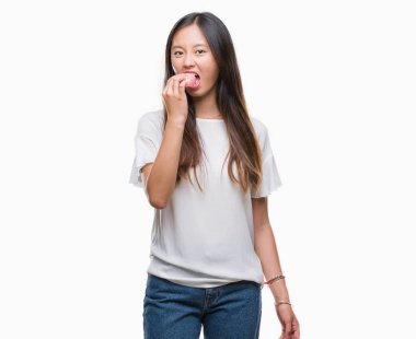 Genç Asyalı kadın akıllı yüzünde ciddi düşünme emin bir ifade ile izole arka plan üzerinde donut yemek