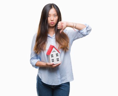 Kızgın yüz, eksi işareti aşağı antipati başparmak ile gösterilen, ret kavramı ile arka plan ev tutan Genç Asyalı kadın gerçek durum Aracısı izole