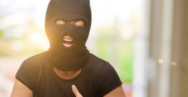 Kendinden emin ve mutlu bir büyük doğal gülümseme gülmek ile yün kar maskesi giyen hırsız terörist kadın