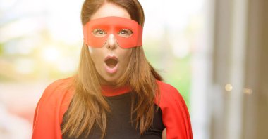 Panik ve korku ifade şokta, orta yaş süper kahraman kadın kırmızı maske ve cape korkuttu