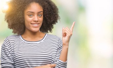 Yüzünde kocaman bir gülümseme ile izole arka plan üzerinde genç afro Amerikalı kadın kameraya bakarak yan el ve parmak ile işaret.