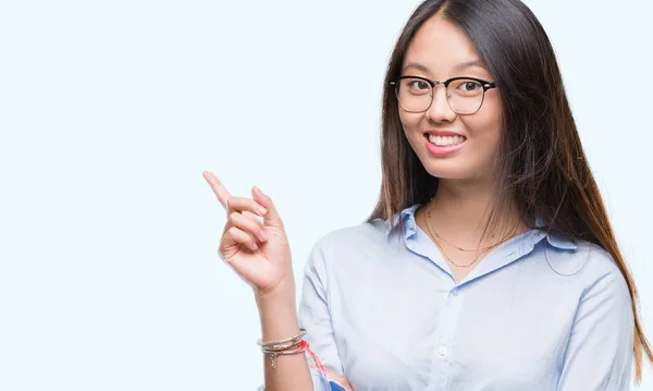 若いアジア ビジネス女性の顔に大きな笑みを浮かべて隔離された背景に眼鏡カメラを見て側に手と指で指しています — ストック写真