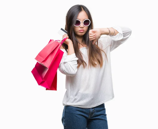 怒った顔 ダウン親指で嫌悪感を示すマイナス記号 拒絶反応の概念と分離の背景の上販売の買い物袋を保持している若いアジア女性 — ストック写真