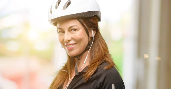中年骑自行车的妇女使用耳机自信和快乐的大自然微笑邀请进入 — 图库照片