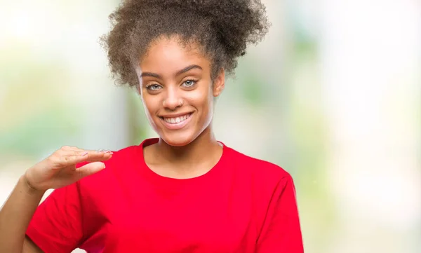 Young afro american woman over isolated background gesturing with hands showing big and large size sign, measure symbol. Smiling looking at the camera. Measuring concept.