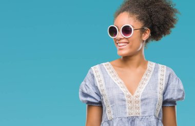 Uzak tarafına yüzünde, doğal ifade gülümseme ile seyir izole arka plan üzerinde gözlük takan genç afro Amerikalı kadın. Kendine güvenen gülüyor.