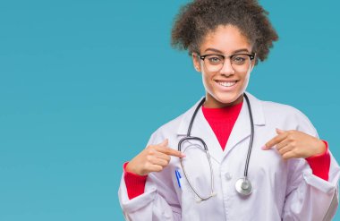 Yüzünde gülümseme ile kendinden emin görünüyorsun, kendini gururlu ve mutlu parmakları ile işaret izole arka plan genç afro Amerikalı doktor kadın.