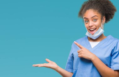 Genç afro Amerikalı doktor kadın üzerinden hayran ve el ile sunulması ve parmak ile işaret ederken kameraya gülümseyen izole arka plan.