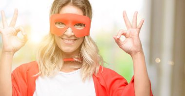 Genç kahraman kadın meditasyon ve gevşeme ifade iki elinle ok işareti jest yapıyor pelerin giyen süper