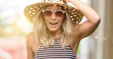 İşaret parmağı ile uzak yan yaz şapka güneş gözlüğü kullanan genç kadın