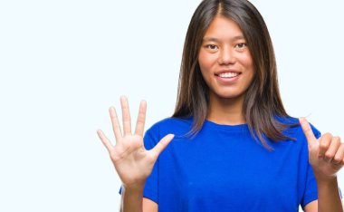 Genç Asyalı kadın gösterilen ve parmakları ile işaret izole arka plan üzerinde kendinden emin ve mutlu gülümseyerek süre 6 numara.