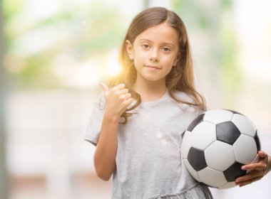 Esmer Latin kız futbol futbol topu ok işareti, başparmak ile parmak, mükemmel işareti yapıyor kocaman bir gülümseme ile mutlu holding