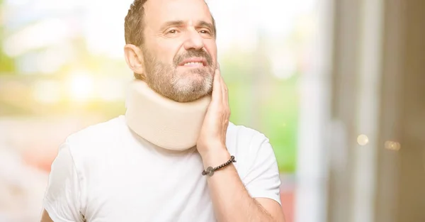 Injured senior man using a neck brace thinking and looking up expressing doubt and wonder