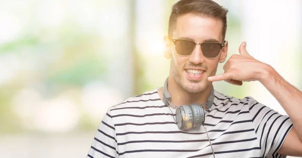 Przystojny Młody Człowiek Noszenie Słuchawek Uśmiechający Się Robi Telefon Gest — Zdjęcie stockowe