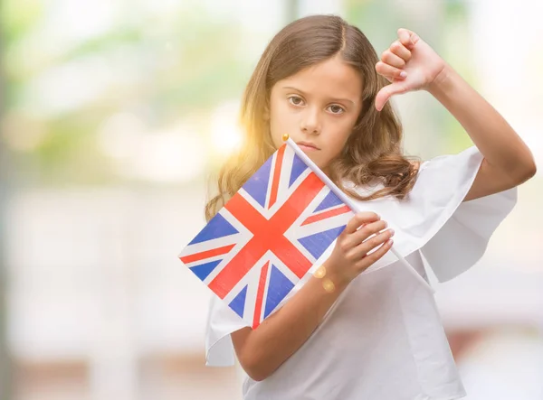 怒った顔 ダウン親指で嫌悪感を示すマイナス記号 拒絶反応の概念でイギリスの旗を保持しているヒスパニックのブルネットの少女 — ストック写真