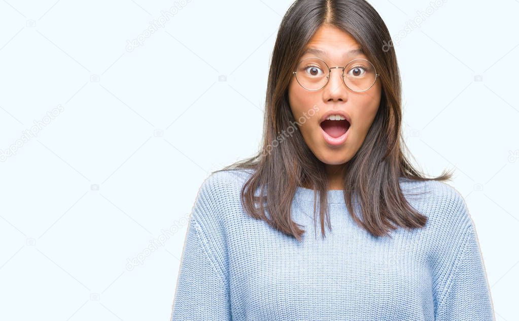 Young asian woman wearing winter sweater over isolated background afraid and shocked with surprise expression, fear and excited face.