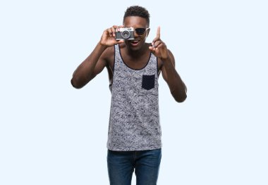 Genç Afro-Amerikan vintage fotoğraf makinesi sürpriz bir fikir tutan adam ya da gülen yüz, bir numara ile işaret parmağı soru