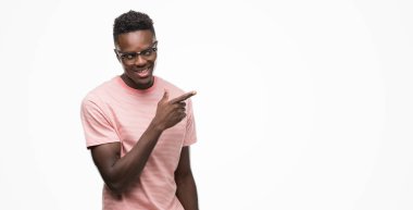 Pembe t-shirt neşeli bir gülümseme ile el ve parmak kadar kameraya bakarak yüzündeki mutlu ve doğal ifade ile yan ile işaret yüz giyen genç Afro-Amerikan adam.