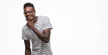 Gözlük ve emin çapraz kollar ve çeneme kaldırdı el ile gülümseme ile kameraya bakarak lacivert t-shirt giyen genç Afro-Amerikan adam. Pozitif düşünce.