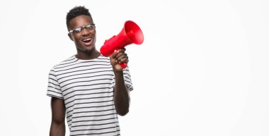 Megafon ile ayakta ve diş gösterilen kendine güvenen bir gülümsemeyle gülümseyerek mutlu bir yüz tutan genç Afro-Amerikan adam