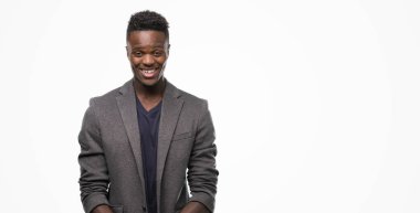 Ayakta ve diş gösterilen kendine güvenen bir gülümsemeyle gülümseyerek mutlu bir yüz ile bir ceket giyen genç Afro-Amerikan adam
