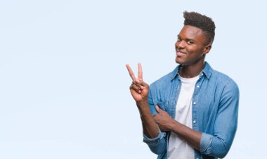 Afrikalı-Amerikalı genç mutlu yüz zafer işareti yaparken kameraya göz kırpıyor ile gülümseyen izole arka plan üzerinde. İki numaralı.