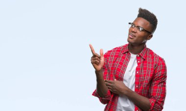 Kameraya bakarak yan el ve parmak ile işaret eden genç Afro-Amerikan adam yüzünde kocaman bir gülümseme ile izole arka plan üzerinde.