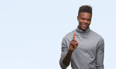 Ve kendinden emin ve mutlu gülümseyerek süre parmak numaralı yukarıyı gösteren izole arka plan üzerinde genç Afro-Amerikan adam.