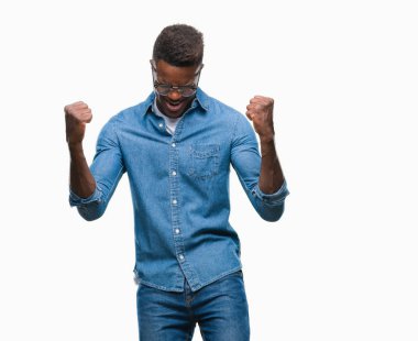 Gülümseyen ve başarı için çığlık genç Afro-Amerikan adam izole arka plan çok mutlu ve heyecanlı kaldırdı, silah ile kazanan jest yapıyor. Kutlama kavramı.