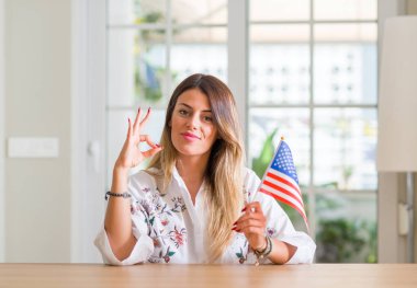 Amerika Birleşik Devletleri parmak, mükemmel sembolü ile ok işareti yapıyor bayrağı genç kadın evde tutan