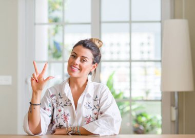 Genç kadın evde gösterilen ve parmak üçüncü ile gülümseyen ise kendinden emin ve mutlu yukarı dönük.