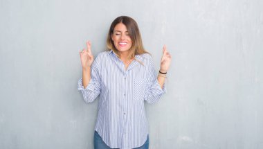 Gri grunge duvar geçiş parmakları umut ve gözler gülümseyen moda iş kıyafeti giymiş genç yetişkin kadın kapalı. Şans ve batıl kavramı.