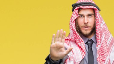 Genç yakışıklı Arap adam uzun saçlı keffiyeh stop yapıyor izole arka plan üzerinde giyen elin avuç ile şarkı. Negatif ve ciddi bir jest yüz ifadesiyle uyarı.