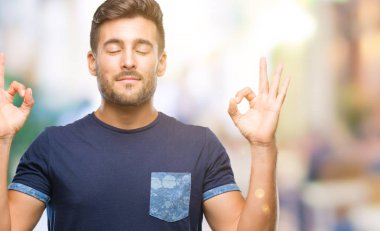 Yakışıklı delikanlı izole arka plan üzerinde dinlenmek ve gülümseyen gözlerle parmak ile meditasyon jest yapıyor kapalı. Yoga kavramı.