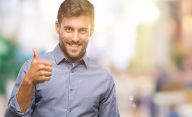 Yakışıklı delikanlı hareketi el ile mutlu yaşasın yapıyor izole arka plan üzerinde. Kameraya bakarak başarı gösteren ile ifade onaylama.