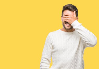 Genç yakışıklı adam gülümsüyor ve gözleri için sürpriz kapsayan yüz el ile gülüyor izole arka plan üzerinde kış kazak giyiyor. Kör kavramı.