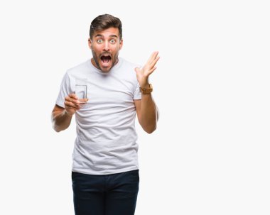 Yakışıklı delikanlı büyük gülümseme ile çığlık zaferini kutluyor ve ellerini kaldırdı izole arka plan çok mutlu ve heyecanlı, kazanan ifade üzerinde bardak su içme