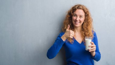 Ok işareti, başparmak ile parmak, mükemmel işareti yapıyor kocaman bir gülümseme ile mutlu süt içme genç Kızıl saçlı kadın