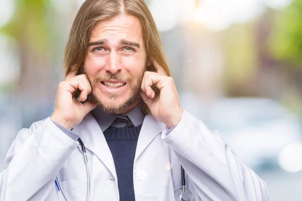 年轻英俊的医生人与长的头发在隔绝的背景覆盖耳朵用手指以恼怒的表示为大声的音乐噪声 聋的概念 — 图库照片