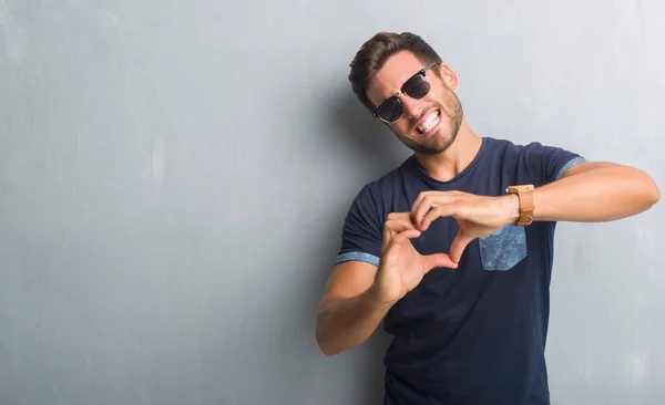 Joven Guapo Sobre Una Pared Grunge Gris Con Gafas Sol — Foto de Stock