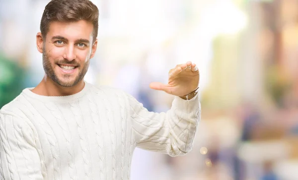 孤立した背景ジェスチャーで示す大きな手と大きなサイズ記号メジャー シンボル上冬のセーターを着ている若いハンサムな男 カメラを見て笑っています 測定概念 — ストック写真