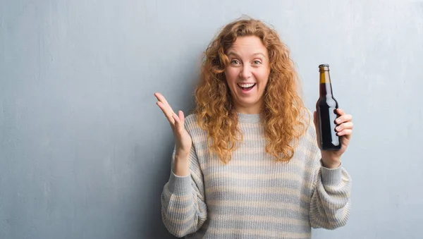 Joven Pelirroja Sobre Pared Grunge Gris Sosteniendo Botella Cerveza Muy — Foto de Stock