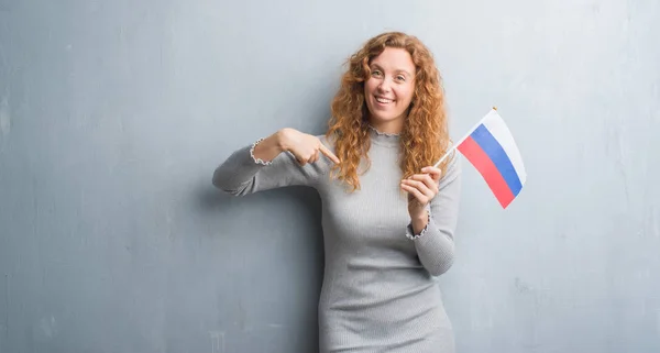 Joven Pelirroja Sobre Pared Grunge Gris Sosteniendo Bandera Rusia Con —  Fotos de Stock